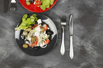 Greek salad feta, cherry tomatoes, olives, cucumbers on a dark background. Top view, copy space. Food background