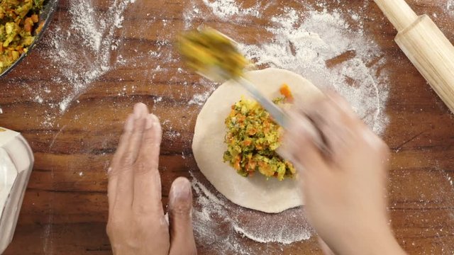 Stuffing chapati and flattening it to prepare paratha
