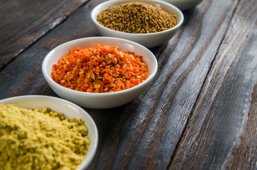 different spices in wooden spoons on a black wooden background