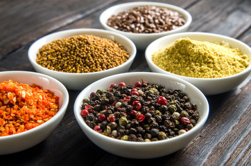 different spices in wooden spoons on a black wooden background