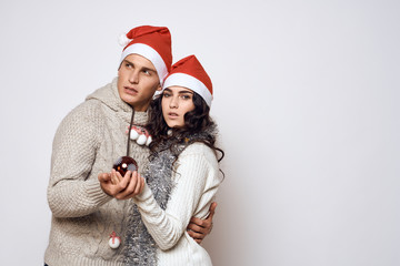 Fototapeta premium man and woman are hugging, holding a Christmas tree decoration in the hand christmas, new year, holiday, couple, light background, free space for copy