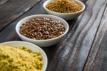 different spices in wooden spoons on a black wooden background