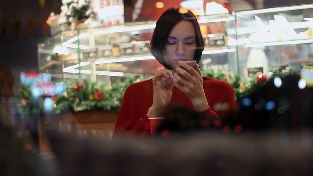 Caucasian young woman typing message using smartphone sitting in cafe