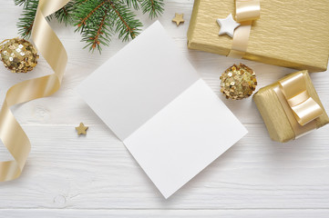 Mockup Christmas greeting card with gold gift ribbon, flatlay on a white wooden background, with place for your text