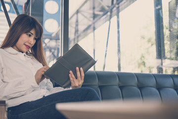 woman sit on sofa in cafe. female student read note in notebook in coffee shop. education, lifestyle, people concept.