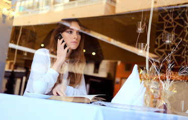 Young brunette talking by phone in a restaurant