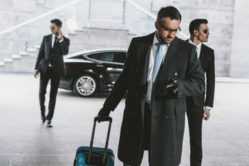 businessman going with travel bag and looking at watch