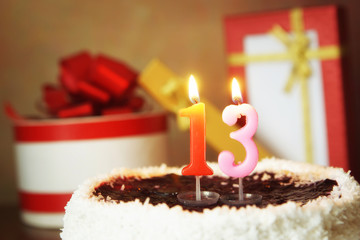 Thirteen years birthday. Cake with burning candle and gifts