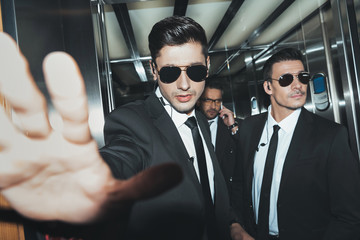 bodyguards stopping paparazzi when celebrity talking by smartphone - obrazy, fototapety, plakaty