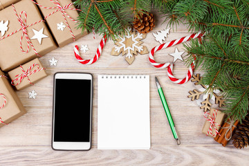 Christmas background with gift boxes, mobile phone with back screen and blank notebook, copy space. Template for new year goal or resolutions. Christmas mockup. Flat lay, top view