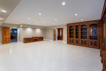 Spacious empty basement area with large custom built bookcase.