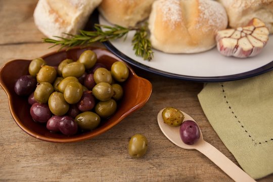 High angle view of olives in plate by bread