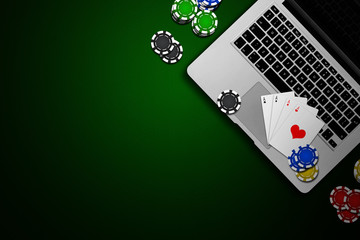 Online casino, laptop, chips cards on a green background. Gambling. View from above.