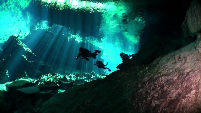Scuba diving in caves of Yucatan cenotes underwater. Clean and clear underground water in reflection of sunlight.