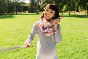 Fototapeta premium happy pregnant asian woman taking selfie at park