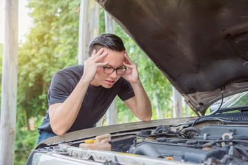 Young asian man with stress face waiting for assistance with his broken car