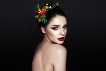Beautiful woman portrait with red and yellow berries on head and with black hair and red lips. - 183493975