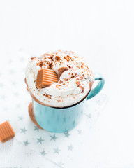 Christmas mood!) Hot chocolate with cream, cinnamon and a toffee in a blue vintage mug on a light background. The best celebration background. Winter xmas holidays concept.