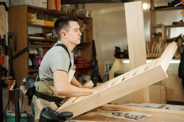 Carpenter carry wooden plank at workshop. Man with carving equipment,