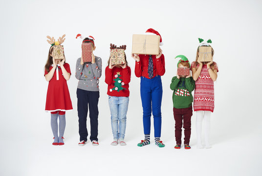 Children holding christmas present in front of their face .