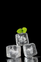 pile of glass ice cube with a mint branch on top on a black background with copy text