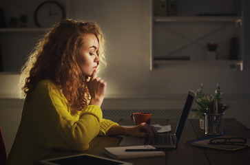 Freelancer working on laptop at home until late evening