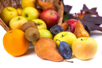 apples and other fruits in a wicker basket on a white background
