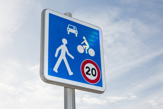 road sign indicates the speed limit and the sharing of the road between pedestrian bike and cars