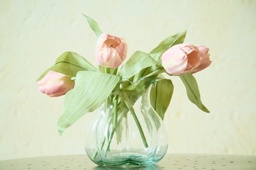 tulips in a glass jug on a metal table on a light background
