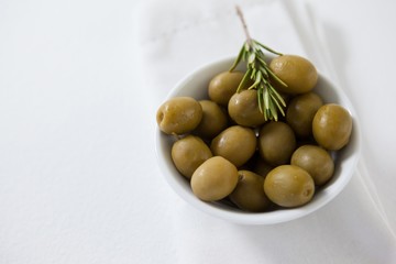 High angle view of green olives with rosemary in bowl 