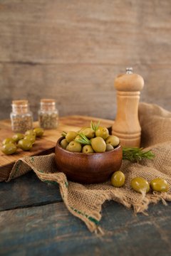 Olives with herb by pepper shaker and cutting board