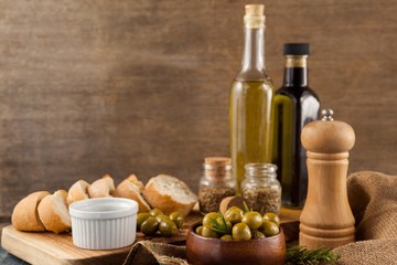 Fototapeta na wymiar Olives with pepper shaker and oil bottles by bread