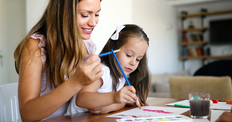 Fototapeta premium Little girl painting with her mother at home