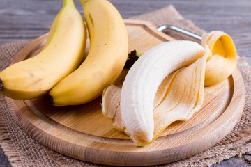 Bananas and peeled banana on a cutting board - Powered by Adobe