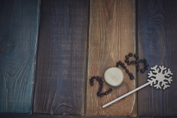 2018 inscription of coffee beans and a wooden circle, a wooden stick with a toy snowflake on a colored wooden background. Copy space