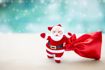 Christmas concept background of Santa Claus with red gift bag over blurred blue water background with snowflake