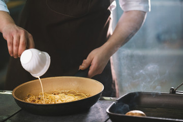 Chef is pouring the sauce into spaghetti