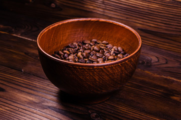 Fototapeta na wymiar Roasted coffee beans in bowl on wooden table