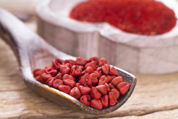 Achiote grains and powder in wooden bowl