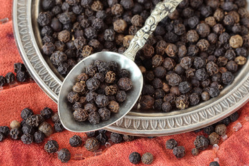 Black pepper on spoon and plate