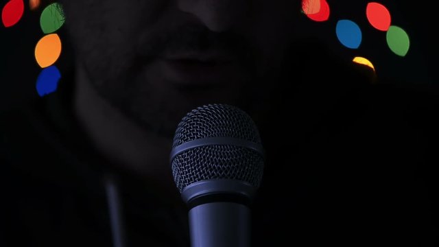 Man sings karaoke in a bar at night with festive bokeh light effect
