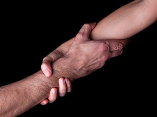 Woman saving, rescuing and helping man by holding or griping the forearm. Female hand and arm pulling up male. Concept of rescue, love, friendship, support, teamwork, partnership, reaching, couple