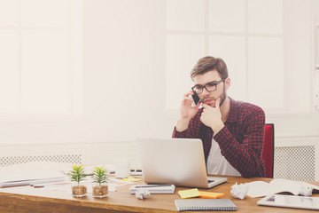 Young serious businessman with laptop in modern white office