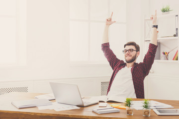 Young successful businessman in white office sitting by the laptop