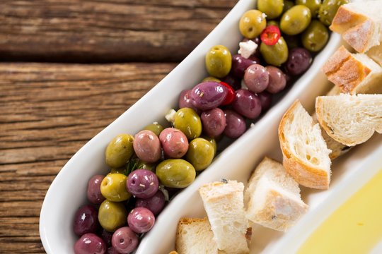 Marinated olives, bread pieces and olive oil in platter