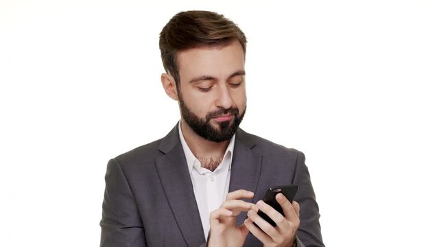 Portrait of attractive man scrolling news feed in his social network using modern mobile device being satisfied with good information over white background in studio closeup. Concept of emotions