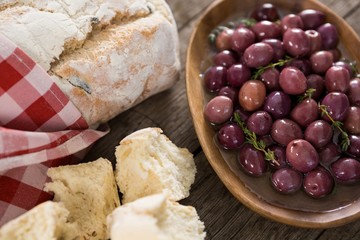 Fototapeta premium Marinated olives with bread loaf on wooden table