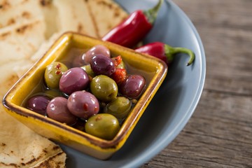 Marinated olives, food and chili pepper on wooden table