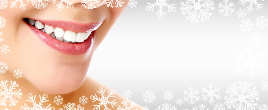 Pretty woman smiling against a grey background with copyspace and snowflakes. Christmas time concept
