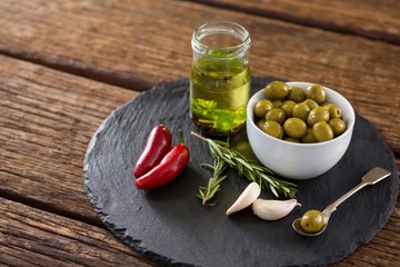Green olives, fresh herbs with olive oil and red chilies on